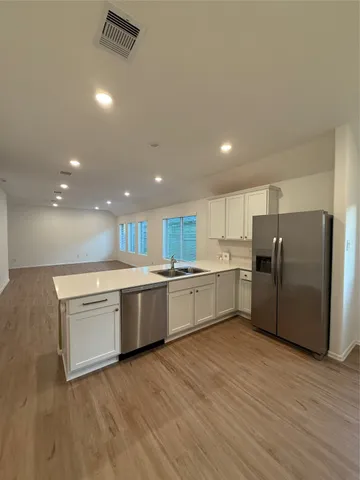 a large kitchen with a large counter top a sink stainless steel appliances and cabinets