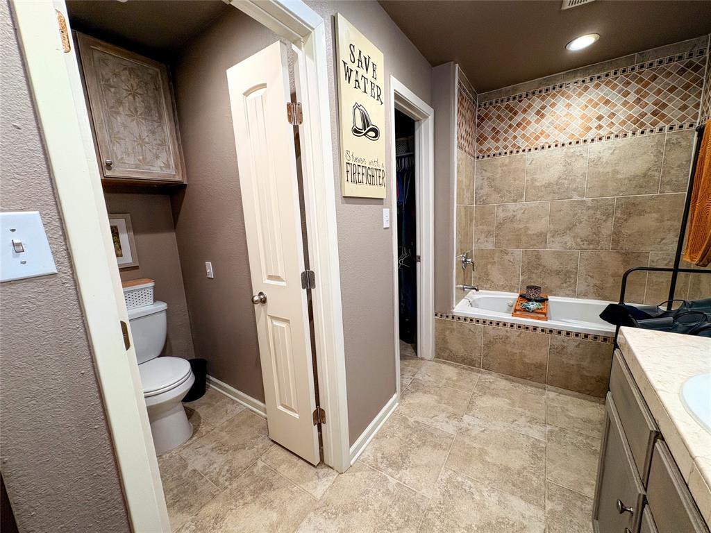 420 Sessums Road Springtown, TX 76082 - Photo 20 of 40 Master bathroom with jetted bath, dual vanity, recessed lighting, and a textured wall