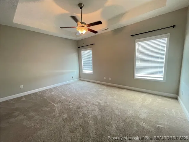 an empty room with a chandelier fan and windows