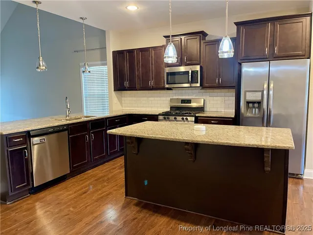 a kitchen with stainless steel appliances wooden cabinets a sink and a counter space