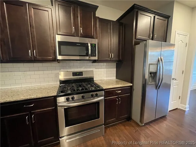 a kitchen with stainless steel appliances granite countertop a stove microwave and refrigerator
