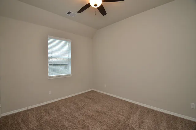 an empty room with a chandelier fan and windows