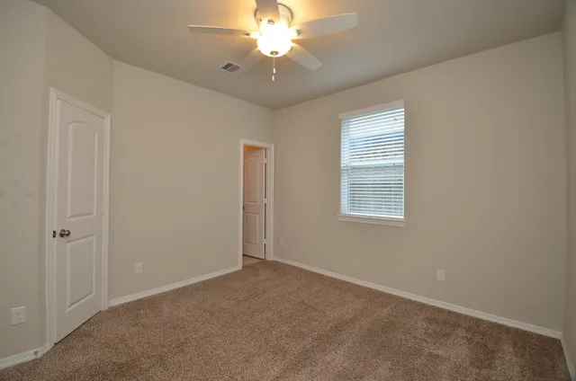 an empty room with windows and fan