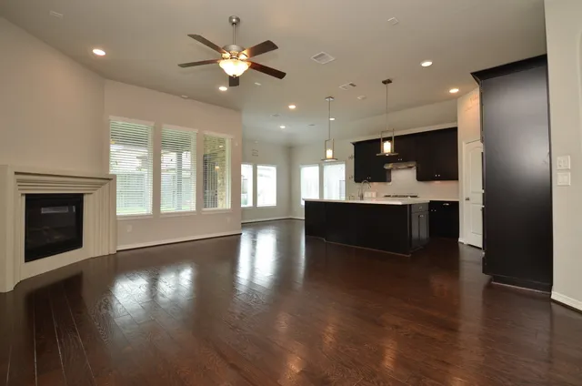 a view of a kitchen and a livingroom with furniture wooden floor a ceiling fan