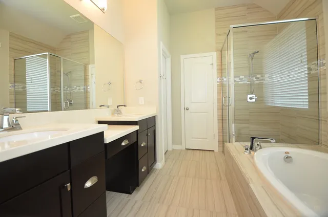 a spacious bathroom with a tub sink shower and mirror