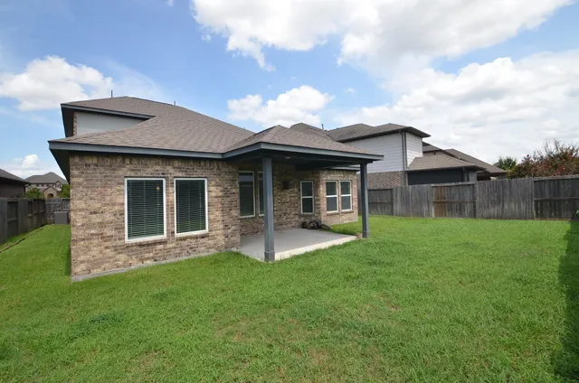 a view of a house with a yard and a large tree