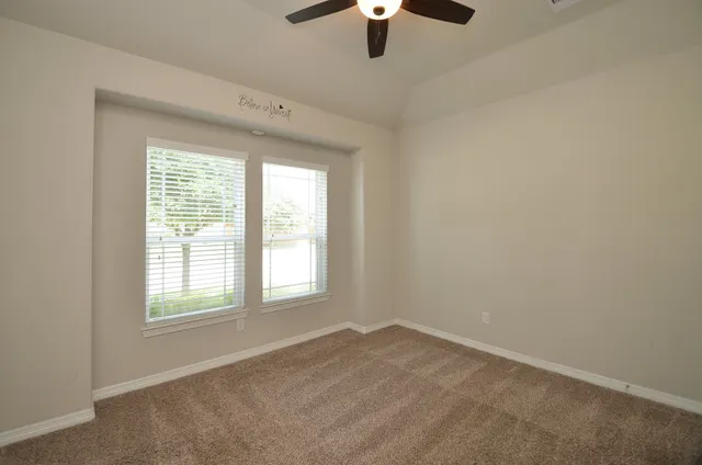 an empty room with a window and a ceiling fan