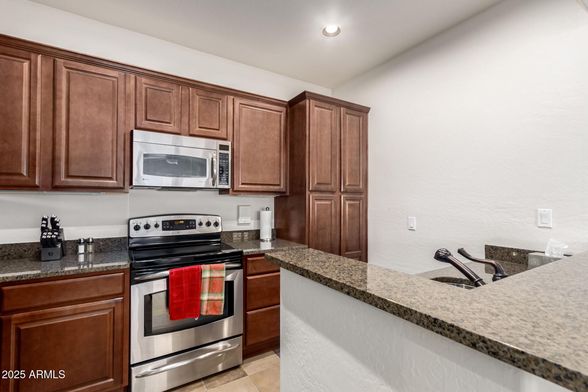 3935 East Rough Rider Road, Unit 1197 Phoenix, AZ 85050 - Photo 9 of 31 a kitchen with stainless steel appliances granite countertop a stove a sink and a microwave