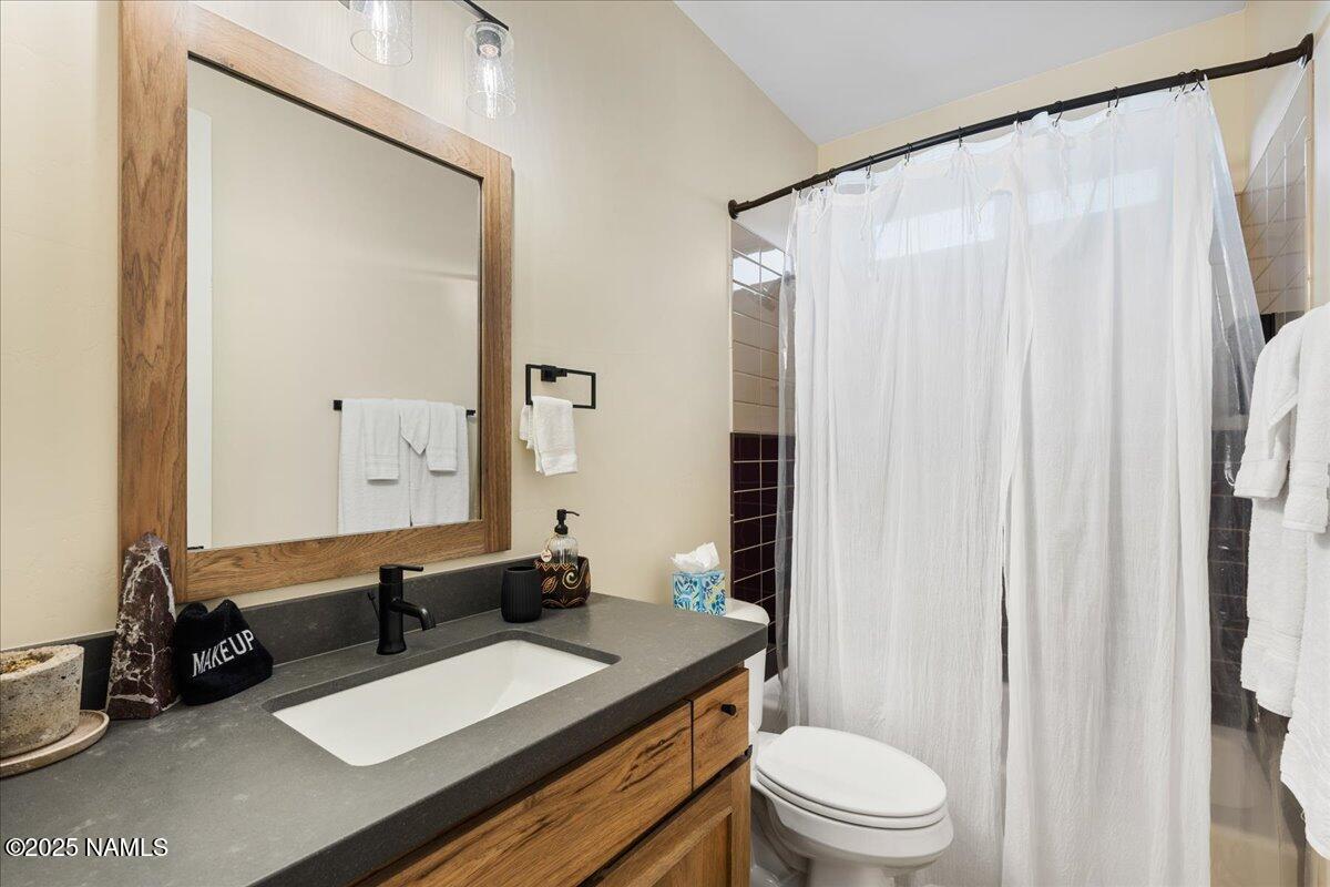 524 Powder Box Road Clarkdale, AZ 86324 - Photo 19 of 32 a bathroom with a sink a toilet a mirror and shower curtain