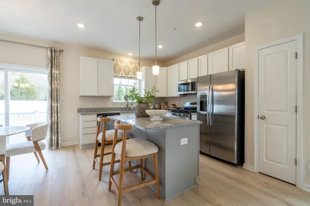 a kitchen with stainless steel appliances a refrigerator a stove a sink a dining table and chairs