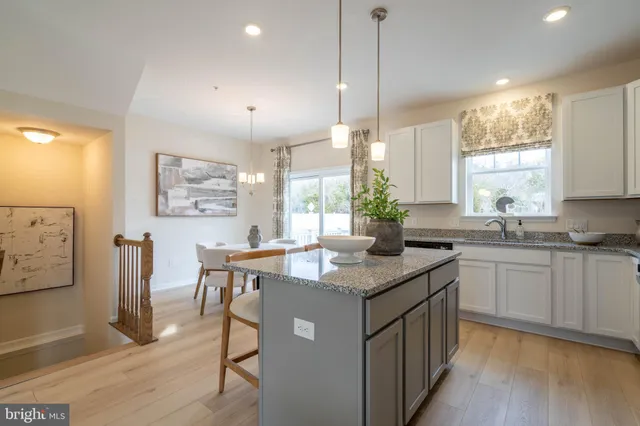 a kitchen with stainless steel appliances granite countertop a sink a stove a refrigerator and island with wooden floor