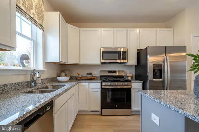 a kitchen with stainless steel appliances granite countertop a sink stove microwave and refrigerator