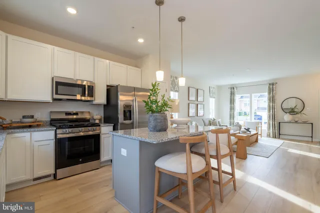 a kitchen with stainless steel appliances granite countertop a stove top oven a sink dishwasher a dining table and chairs with wooden floor