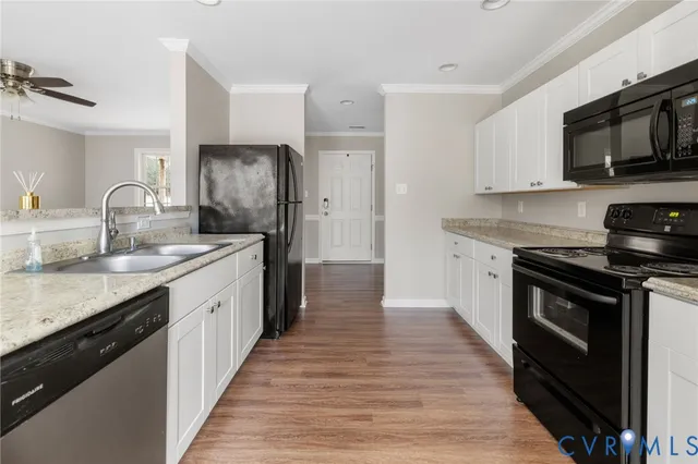 a kitchen with stainless steel appliances granite countertop a stove top oven a sink dishwasher and a refrigerator with wooden floor