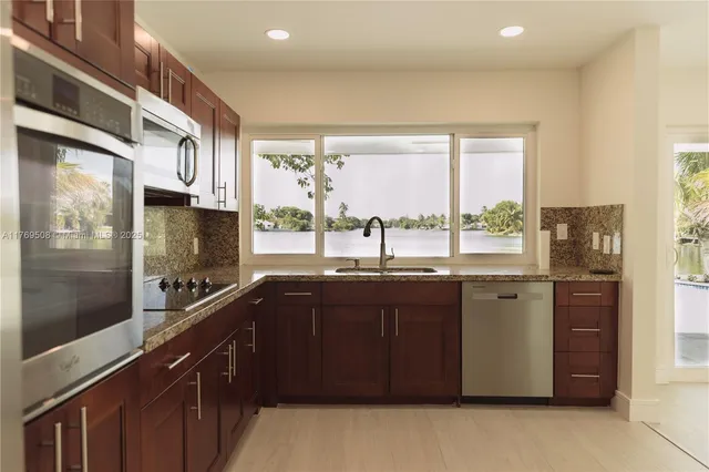 a kitchen with stainless steel appliances granite countertop a refrigerator a sink and wooden cabinets