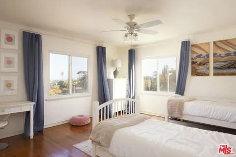 a bedroom with a bed and a large window with wooden floor