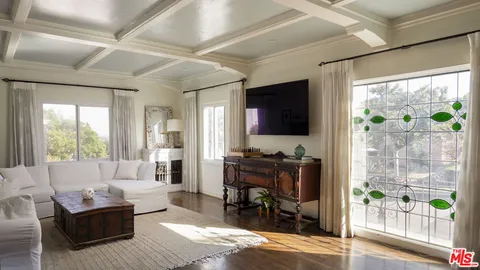 a living room with furniture a flat screen tv and a floor to ceiling window