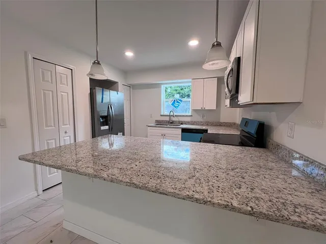 a kitchen with kitchen island granite countertop a sink a counter top space and cabinets
