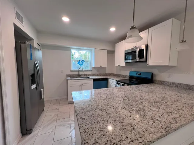 a kitchen with stainless steel appliances granite countertop a refrigerator a oven a sink a stove and a refrigerator