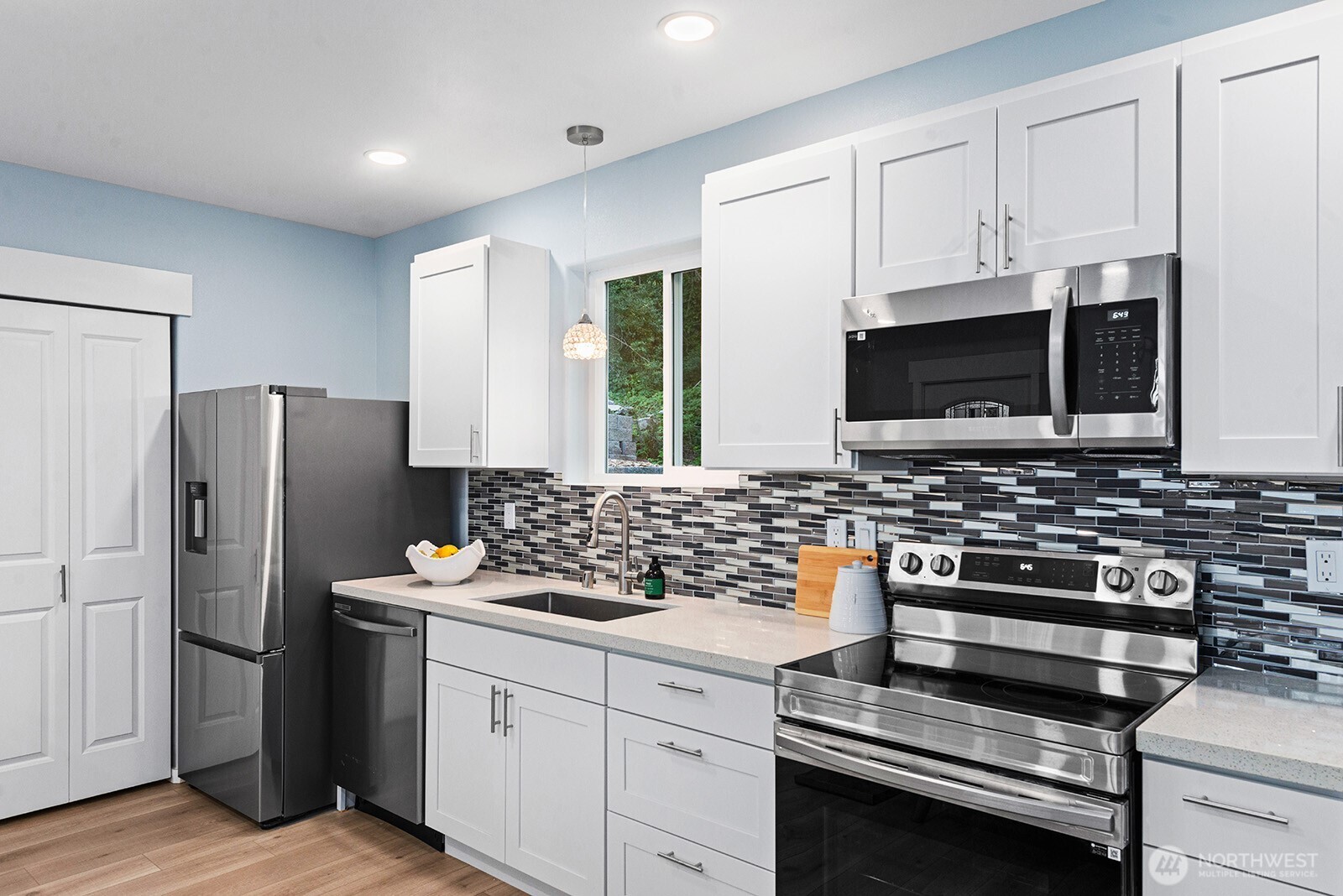 3265 31st Avenue Southwest Seattle, WA 98126 - Photo 8 of 18 a kitchen with stainless steel appliances a stove a microwave and white cabinets