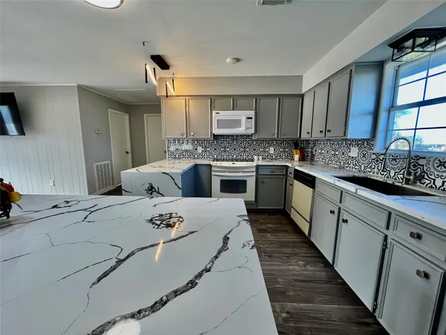 a kitchen with stainless steel appliances granite countertop a sink a stove and a refrigerator