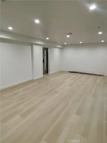 an empty room with wooden floor and natural light