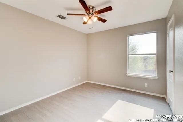 an empty room with a window and a fan