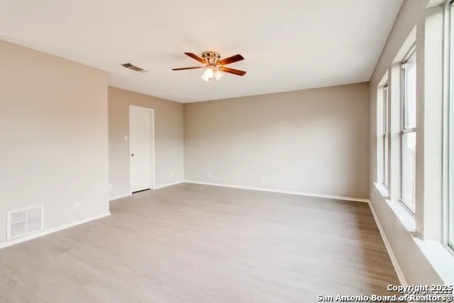 an empty room with windows and chandelier fan