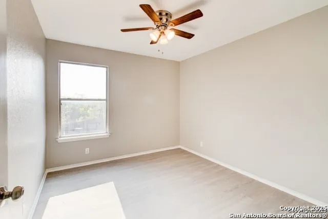 an empty room with a window and a fan