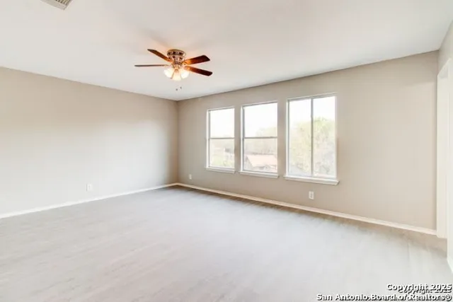 an empty room with windows and ceiling fan