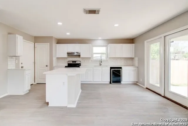 a kitchen with granite countertop a stove top oven and refrigerator
