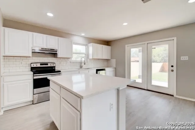 a kitchen with cabinets appliances a sink and a window