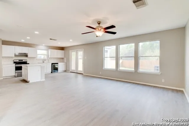 a view of empty room with kitchen and window