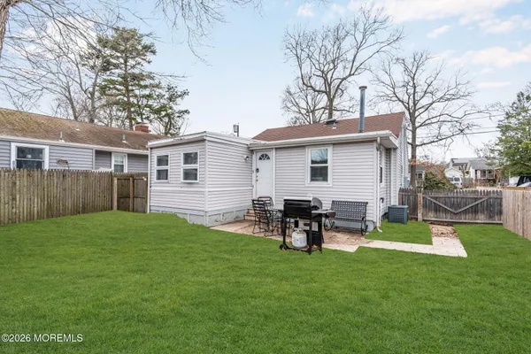 a view of a backyard with table and chairs and a barbeque with wooden fence