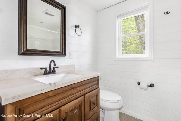 a bathroom with a granite countertop toilet sink and mirror
