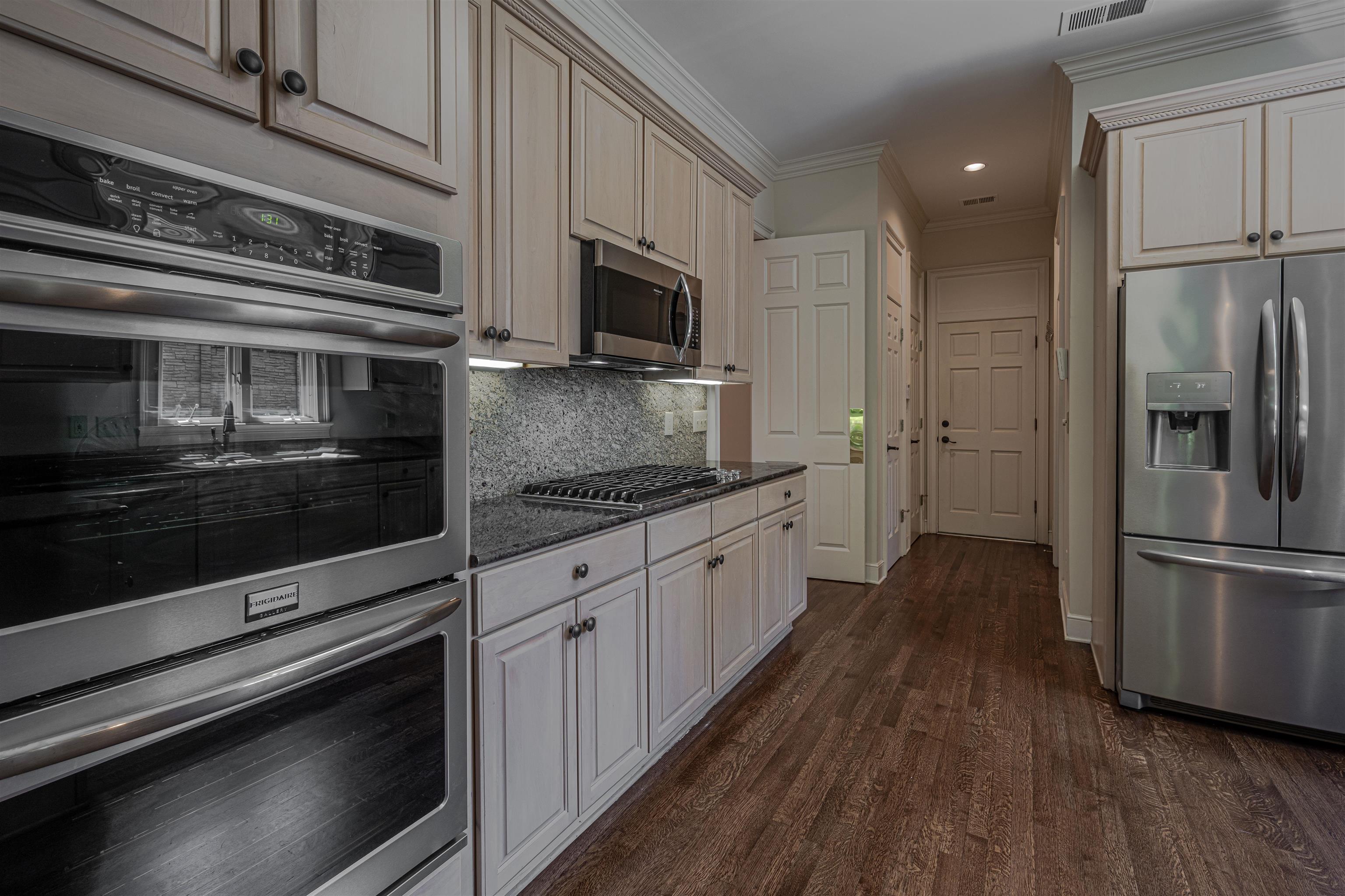 269 North Perkins Road Memphis, TN 38117 - Photo 12 of 40 Kitchen with dark stone counters, ornamental molding, appliances with stainless steel finishes, dark hardwood / wood-style floors, and tasteful backsplash