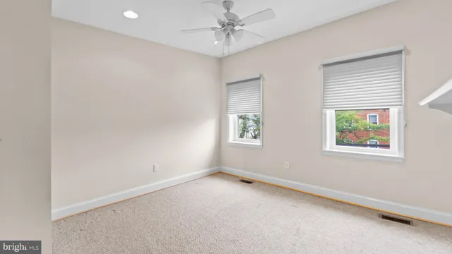 an empty room with windows and ceiling fan