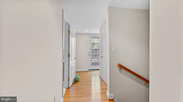 a view of a hallway with wooden floor and a bathroom