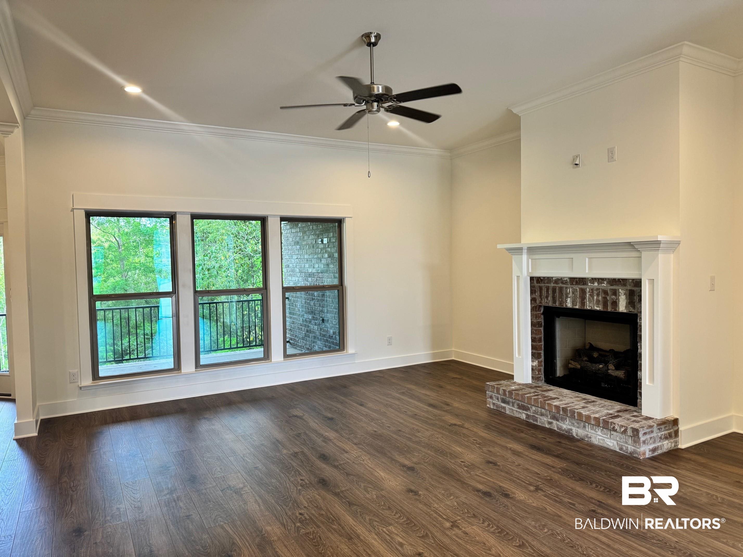 12248 Exbury Way Daphne, AL 36527 - Photo 5 of 63 Unfurnished living room with ceiling fan, a brick fireplace, dark wood finished floors, and ornamental molding