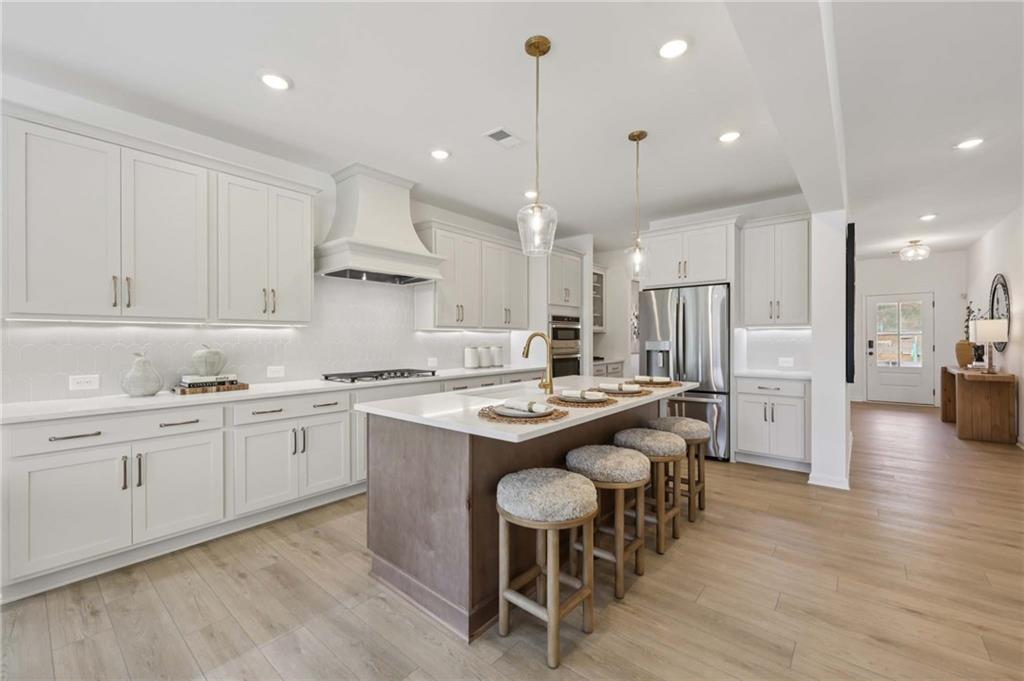 6205 Kismet Road Buford, GA 30518 - Photo 13 of 43 a kitchen with stainless steel appliances granite countertop white cabinets and wooden floor