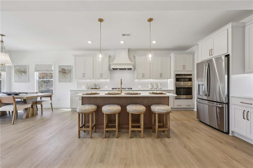 6205 Kismet Road Buford, GA 30518 - Photo 14 of 43 a kitchen with stainless steel appliances granite countertop a dining table chairs refrigerator and sink