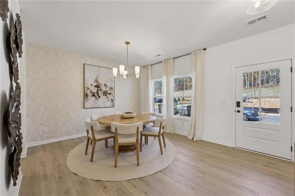6205 Kismet Road Buford, GA 30518 - Photo 18 of 43 a dining room with furniture a chandelier and wooden floor