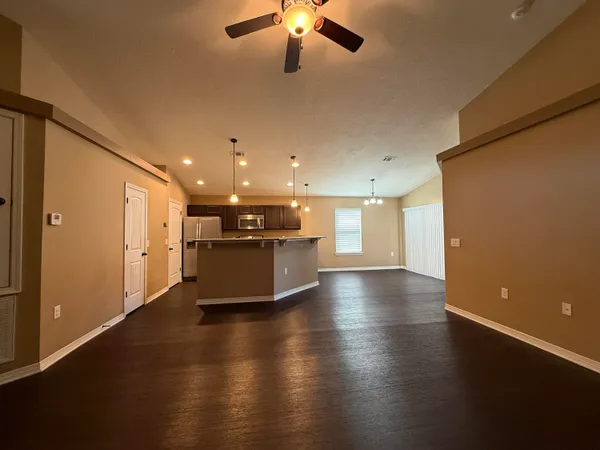 a view of a livingroom with a stove wooden floor and a ceiling fan