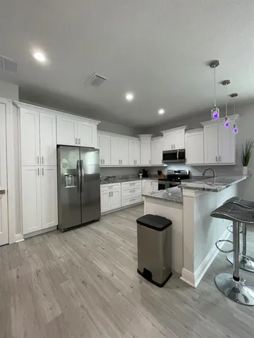 a kitchen with stainless steel appliances a stove a sink a refrigerator and chairs