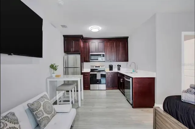 a kitchen with stainless steel appliances granite countertop a stove top oven a sink dishwasher a dining table and chairs with wooden floor