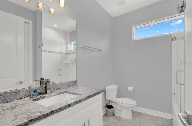 a bathroom with a granite countertop toilet and a sink