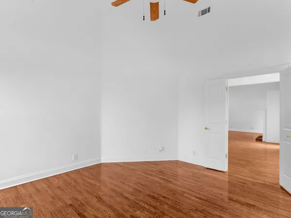 a view of empty room with wooden floor and fan