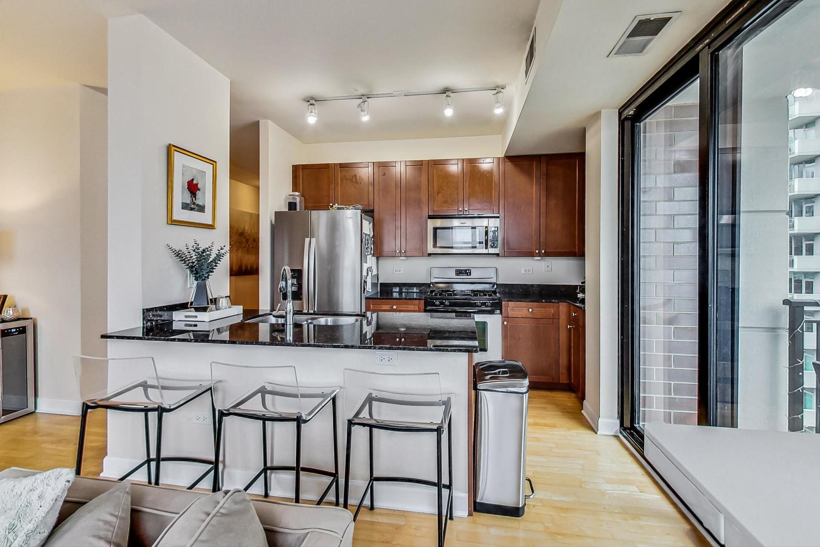 451 West Huron Street, Unit 1201 Chicago, IL 60654 - Photo 7 of 18 a kitchen with stainless steel appliances kitchen island granite countertop a refrigerator and microwave
