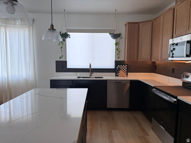 774 West 480 South American Fork, UT 84003 - Photo 17 of 76 Kitchen featuring an expansive island with a white countertop, coordinating perimeter countertops, light wood-finish flooring, and a mix of black and natural wood cabinetry