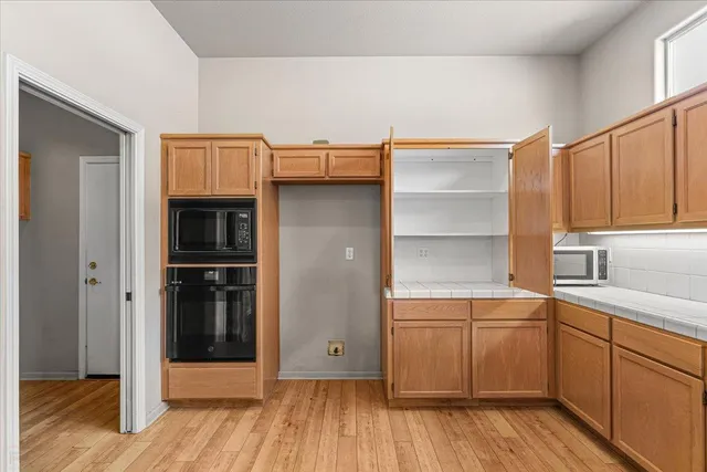 a view of a big room with wooden floor and a kitchen